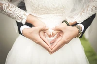 Mãos formando um coração: Uma celebração do amor em trajes de casamento