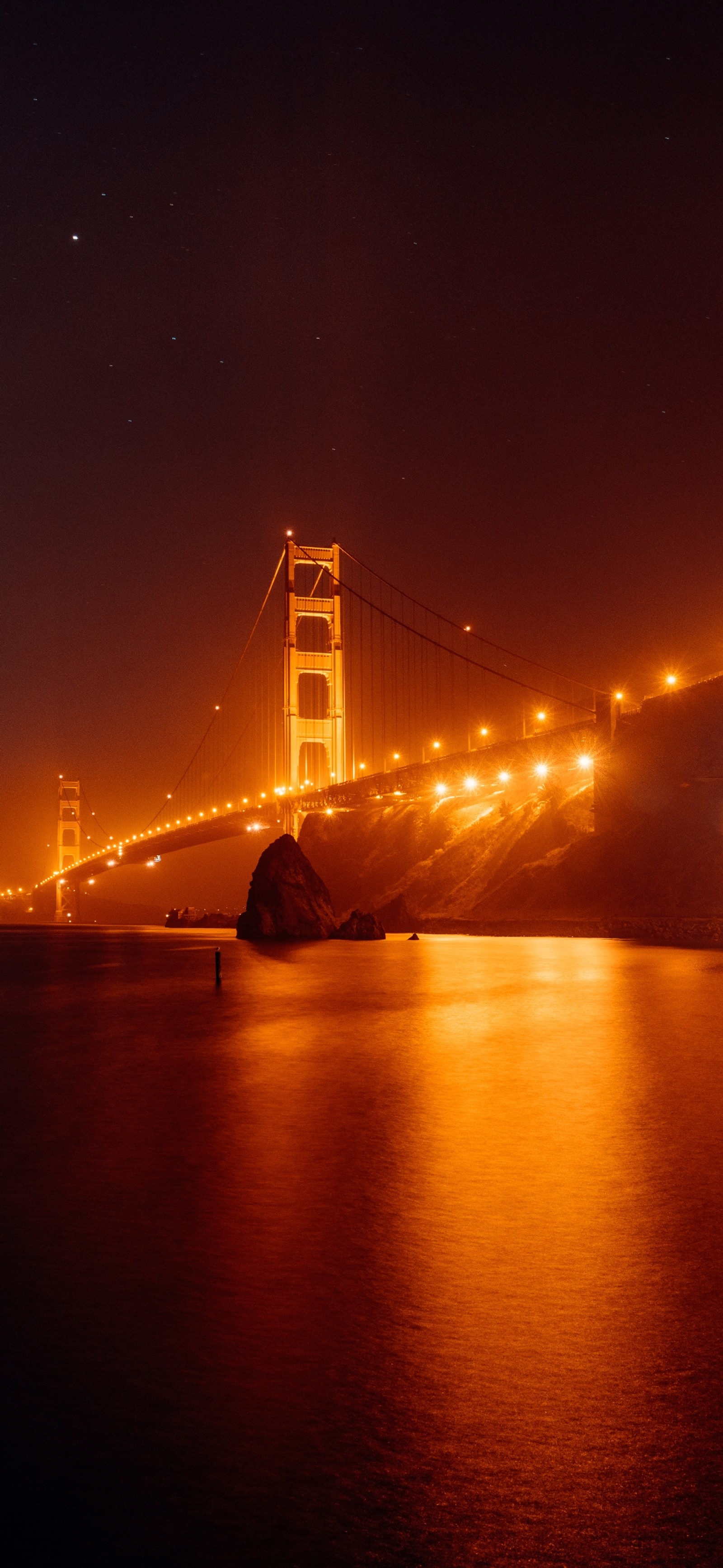 Arafed view of a bridge at night with a bright light (night, golden gate bridge, water, atmosphere, amber)