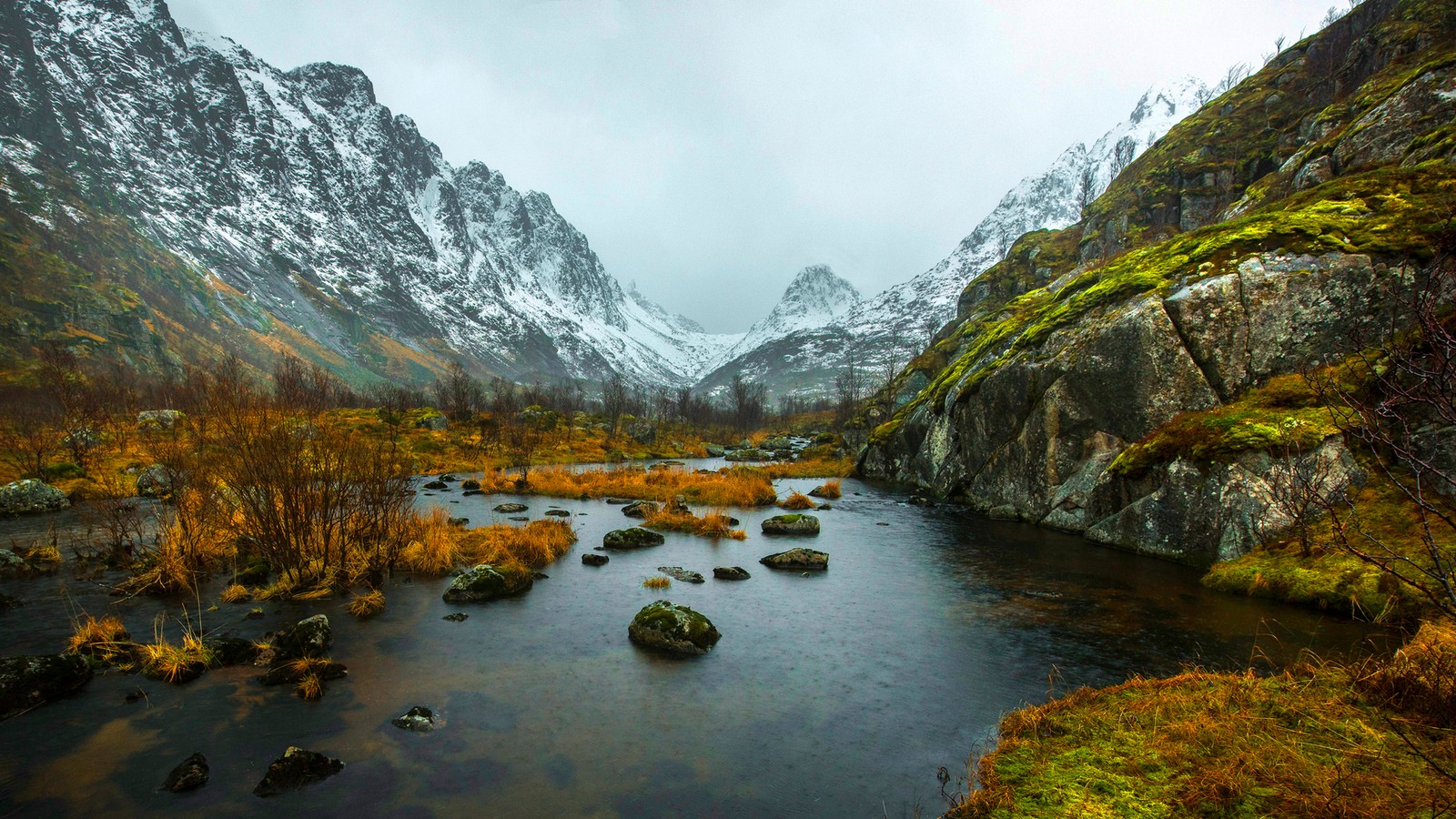 Uma vista de um rio correndo por um vale com montanhas cobertas de neve ao fundo (montanha, lofoten, rio de montanha, wild, natureza)