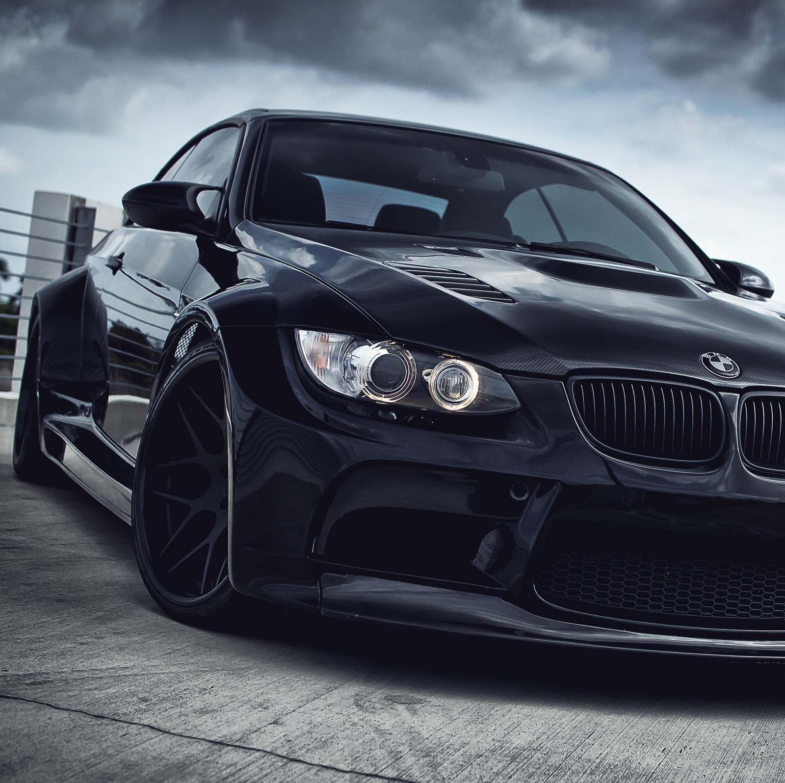 A close up of a black bmw car parked on a parking lot (2014, black, bmw, car, clouds)