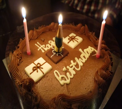 Gâteau d'anniversaire au chocolat avec des bougies et des décorations festives.