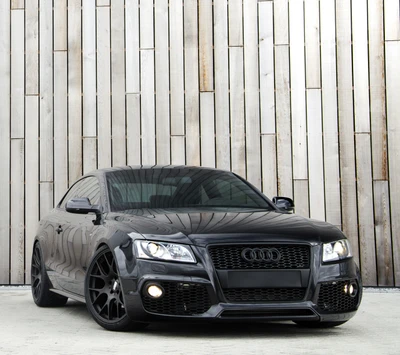 Sleek Black Audi with Custom Wheels Against a Wooden Backdrop