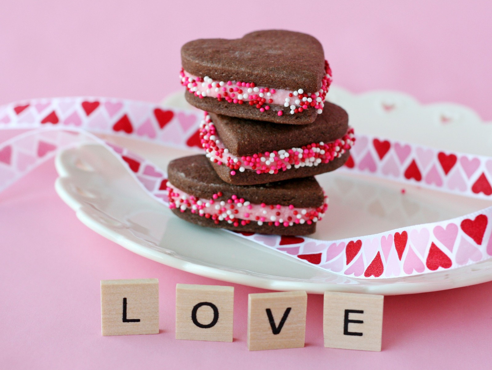 Há três biscoitos em um prato com a palavra amor (bolo, fofo, corações, carta, amor)