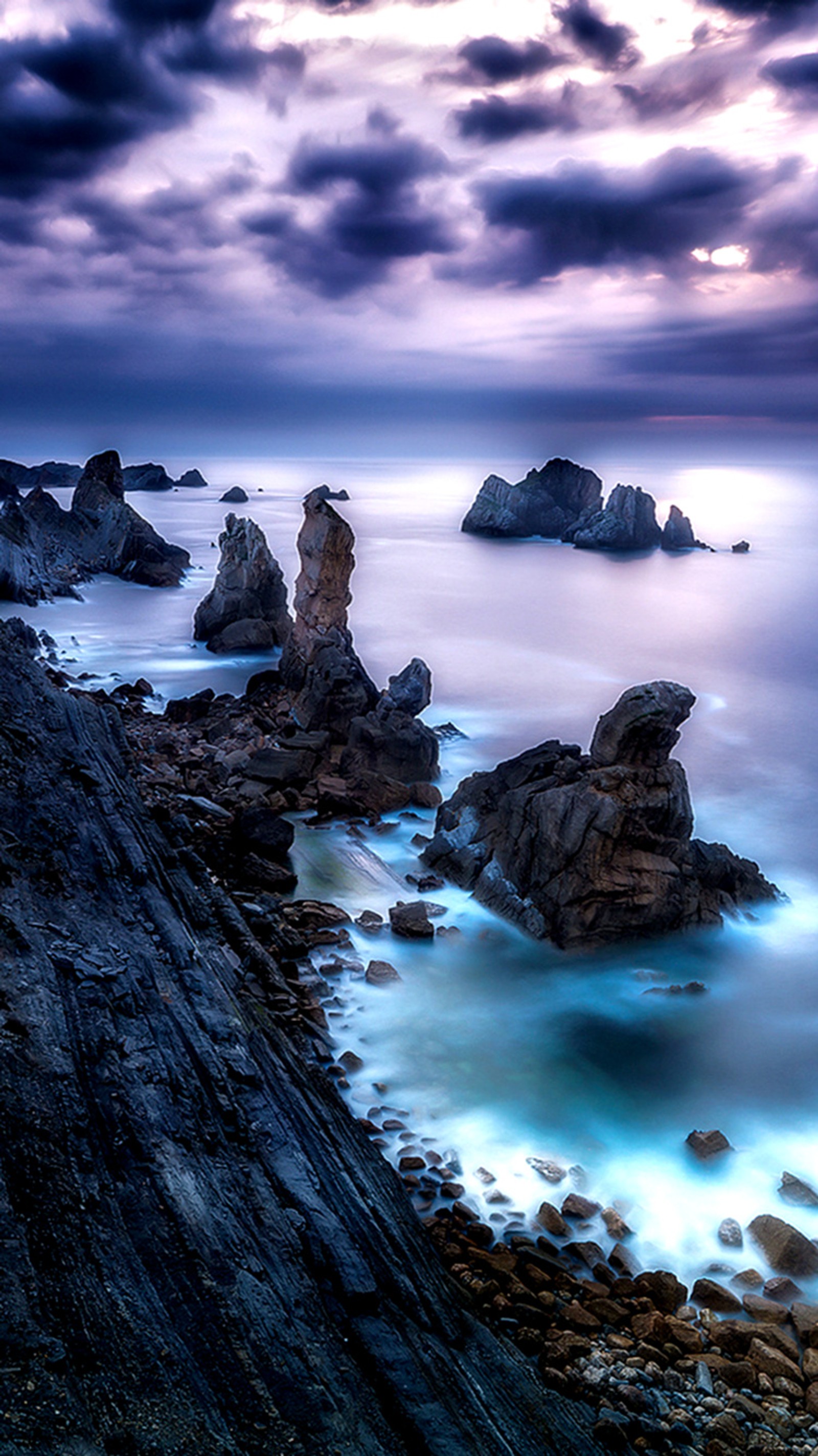 There are rocks on the shore of the ocean under a cloudy sky (magic, storm)