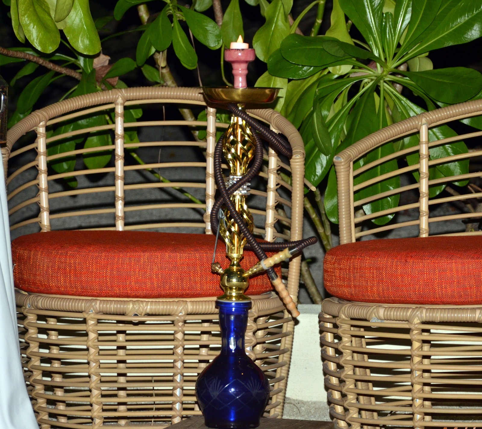 Há um vaso azul com uma vela em uma mesa (open air, shisha, fumaça)