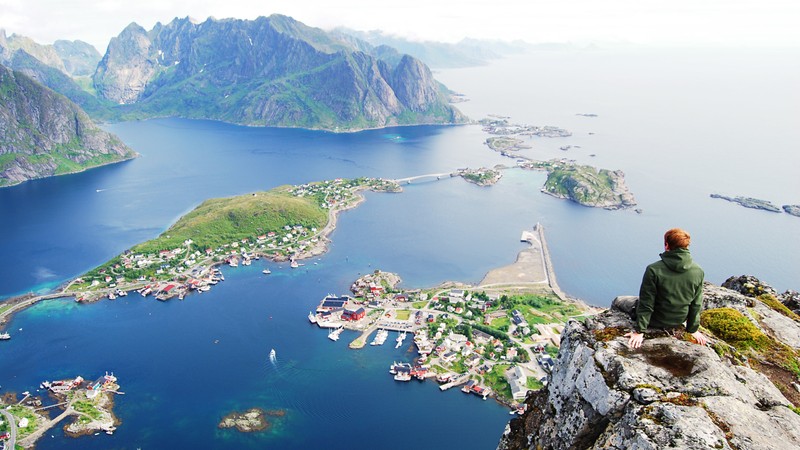 Арабский мужчина сидит на утесе, глядя на большое водоем (лофотены, lofoten, фьорд, водные ресурсы, мыс)