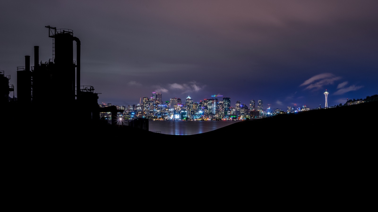 Una vista del horizonte de la ciudad por la noche con un río en primer plano (agua, noche, cielo, asentamiento humano, ciudad)