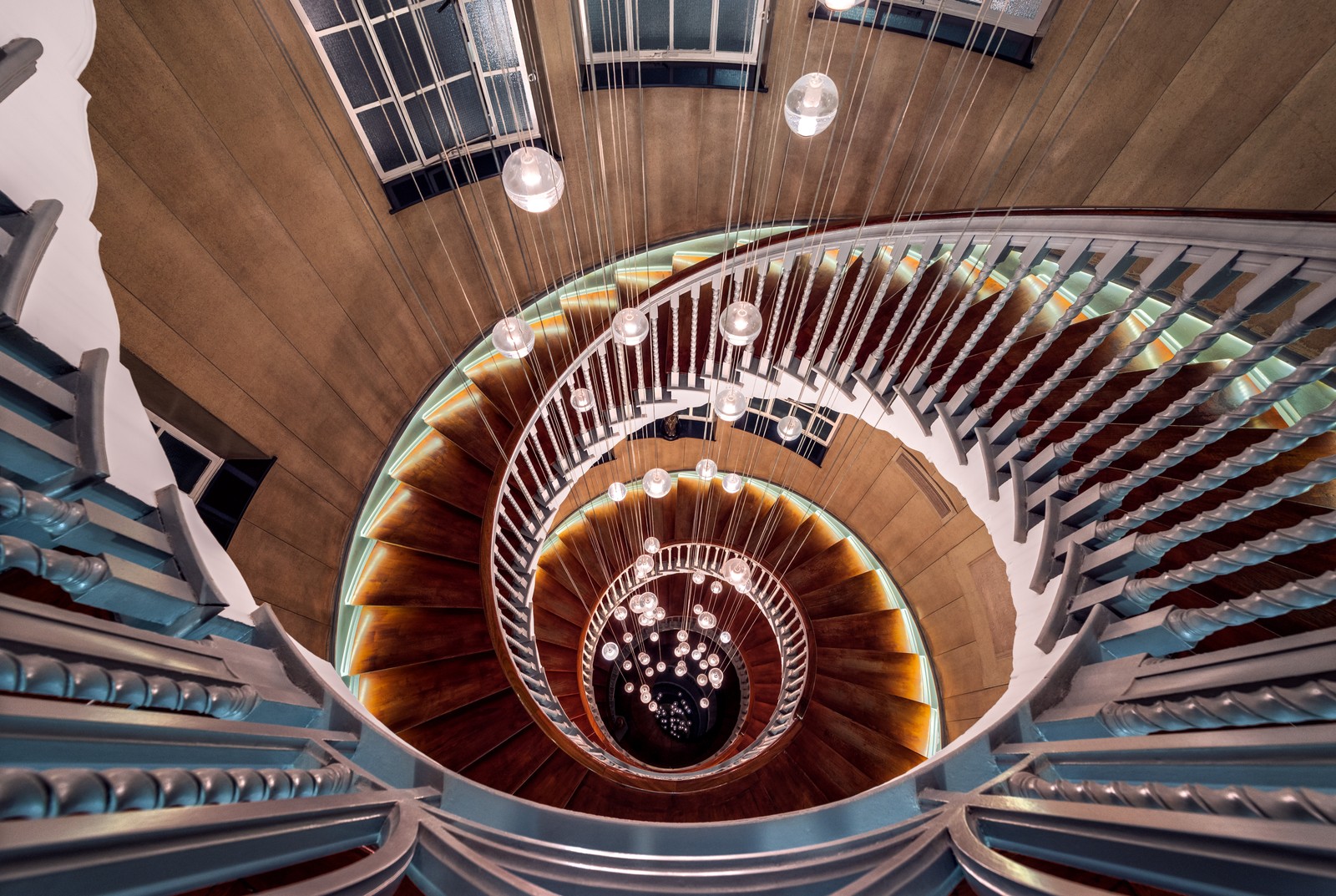 Une vue d'un escalier en colimaçon avec un sol en bois et un puits de lumière (en bois, escalier en colimaçon, étapes, lumières, regarde en bas)