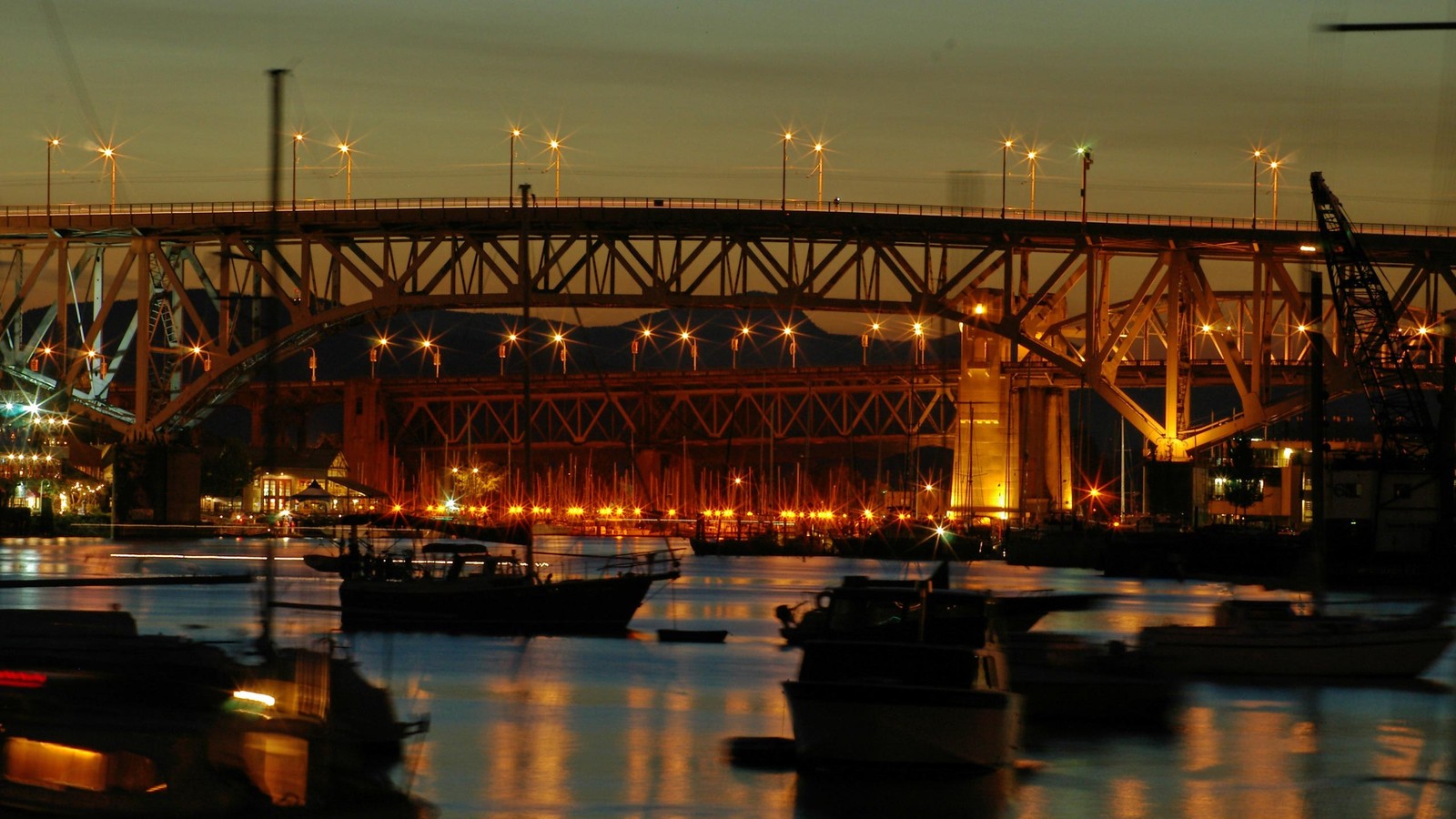 Barcos estão ancorados na água sob uma ponte à noite (ponte, noite, via navegável, flúmen, reflexo)