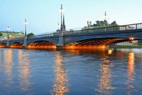 Beleuchtete Bogenbrücke, die sich im ruhigen Wasser bei Dämmerung spiegelt