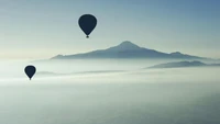 Voo sereno de balão de ar quente sobre montanhas enevoadas