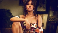 Camila Cabello exala confiança em um top floral de ombro a ombro, capturada em um ambiente vibrante e artístico.