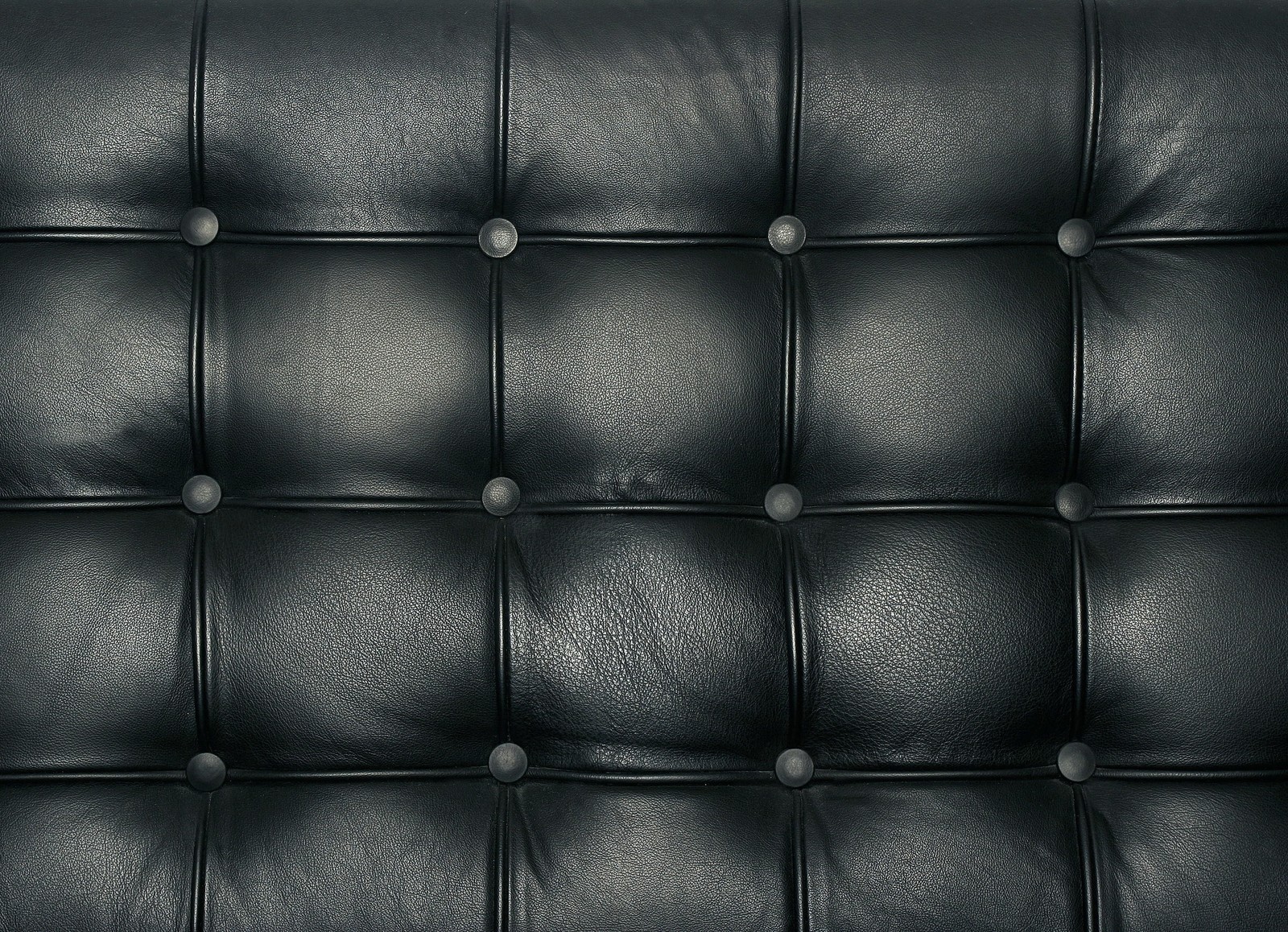 A close up of a black leather couch with buttons (leather, couch, black, clothing, metal)