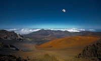 Majestosa cadeia de montanhas sob um céu claro, com a lua surgindo acima de um platô dramático e nuvens cobrindo o vale abaixo.