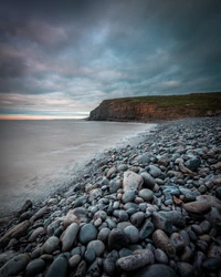 Rocky Shoreline at Dusk with Dramatic Cliffs and Calm Waters