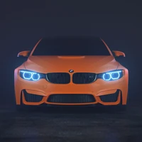 Striking front view of an orange BMW M4, featuring prominent grille and distinctive blue automotive lighting.