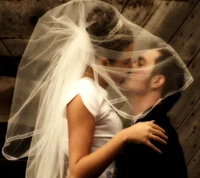 A tender kiss shared between a bride and groom, enveloped in a delicate veil.