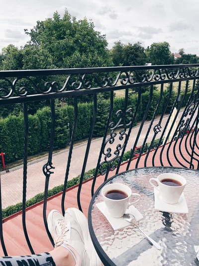 Gelassene Balkonszene mit Kaffeetassen und Eisenzaun