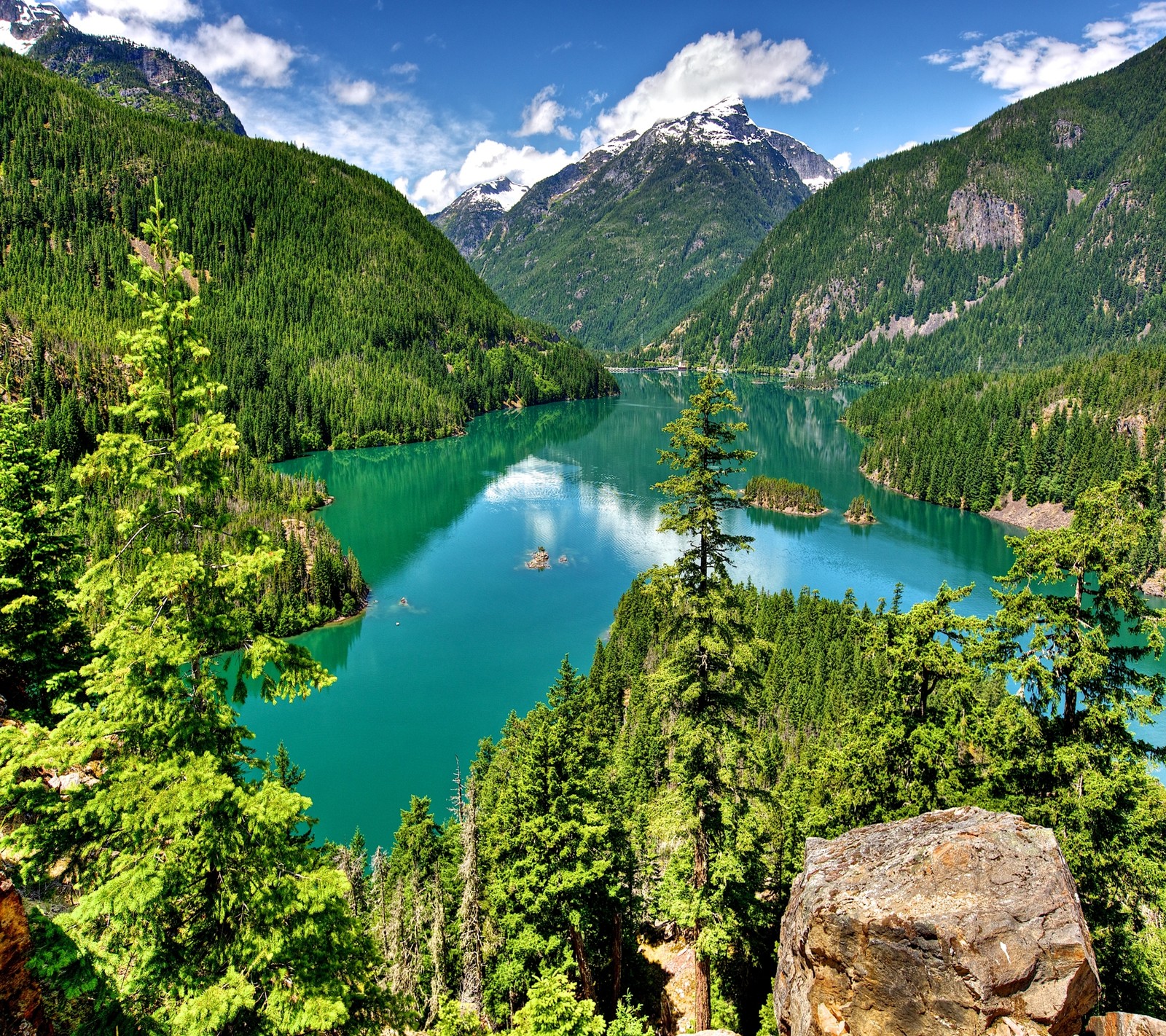 Uma vista de um lago cercado por árvores e montanhas (lago, montanha, natureza, céu, água)