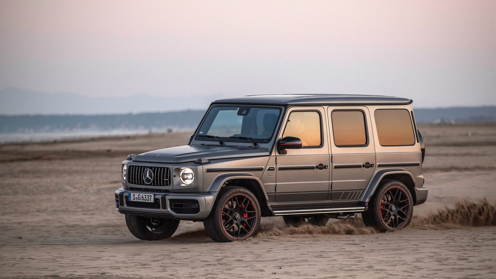 Nahaufnahme eines silbernen mercedes g-klasse, der an einem sandstrand fährt (auto, mercedes benz, offroad, jeep, mercedes benz g class)