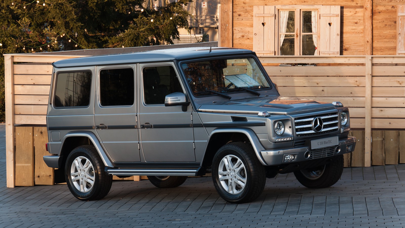 Um mercedes g-class suv estacionado em frente a uma cerca de madeira (carro, mercedes benz g class, exterior automotivo, mercedes benz)