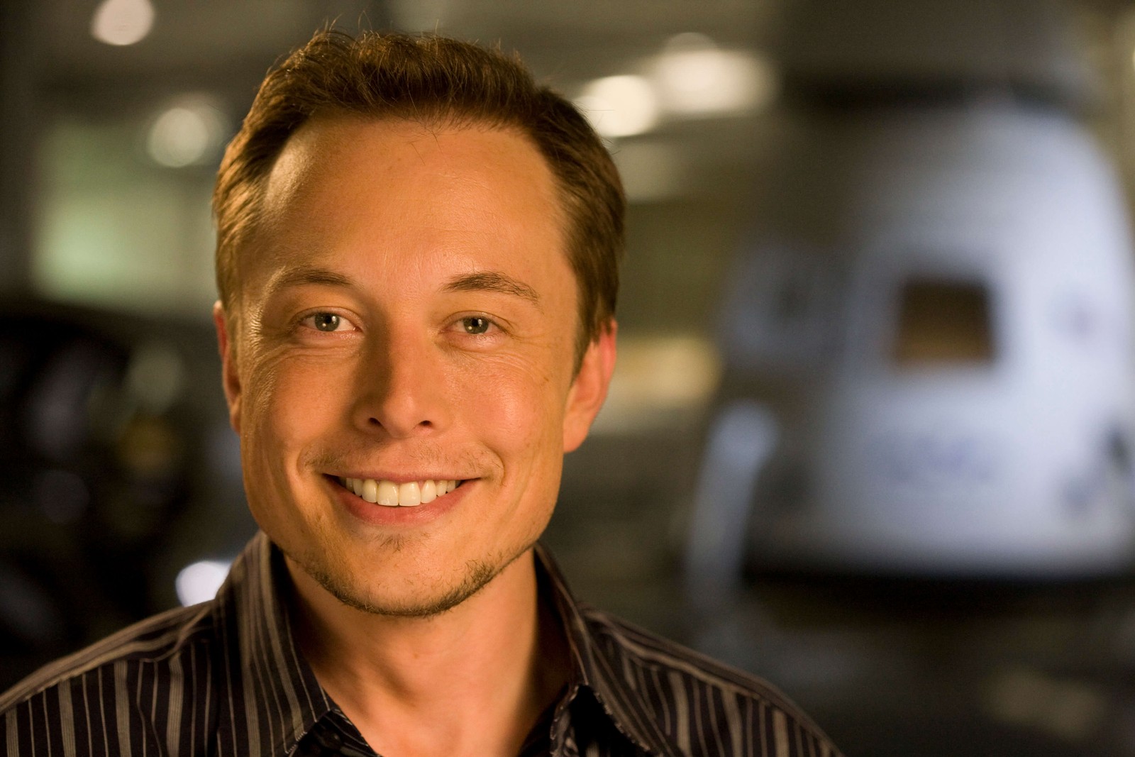 Ein arabischer mann in einem schwarzen hemd, der in einem raum lächelt (elon musk, spacex, gesicht, gesichtsausdruck, lächeln)