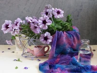 Naturaleza muerta vibrante con petunias moradas y textiles elegantes