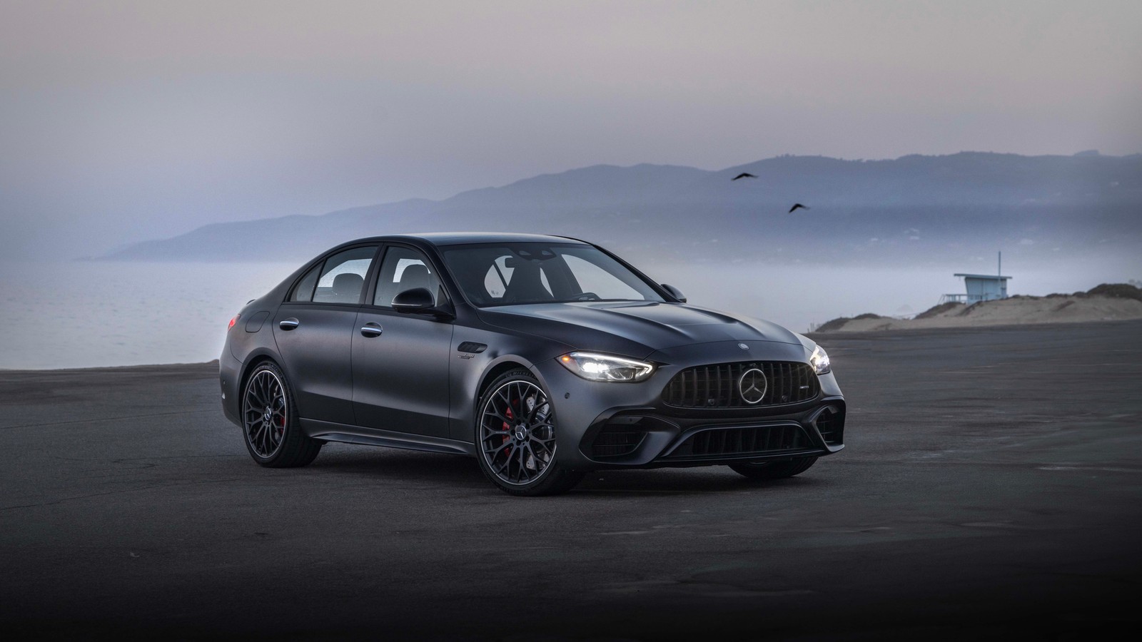 The mercedes amg gts is parked on a beach near the water (mercedes amg c 63 s e performance, 2024, 5k, 8k, cars)