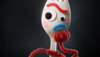 Forky de Toy Story 4, un personnage fantaisiste fabriqué à partir d'une fourchette, avec des yeux expressifs et des bras en pipe cleaners colorés.