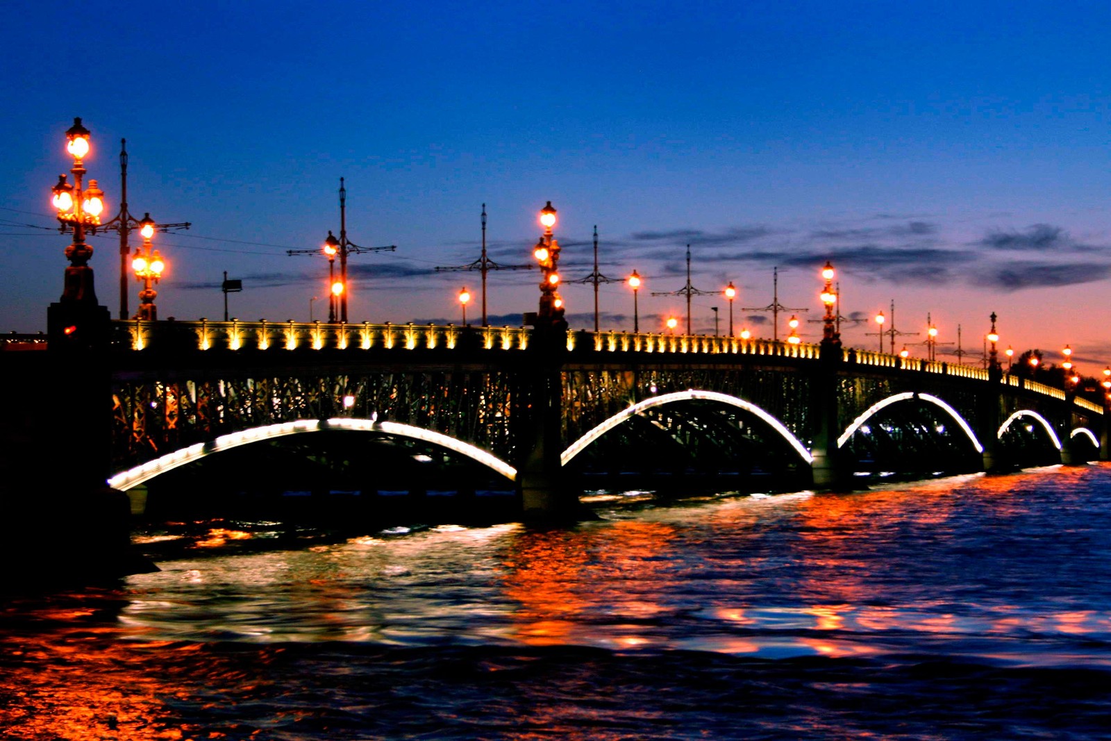 Uma ponte arqueada sobre a água com luzes à noite (são petersburgo, saint petersburg, turismo, marco, noite)