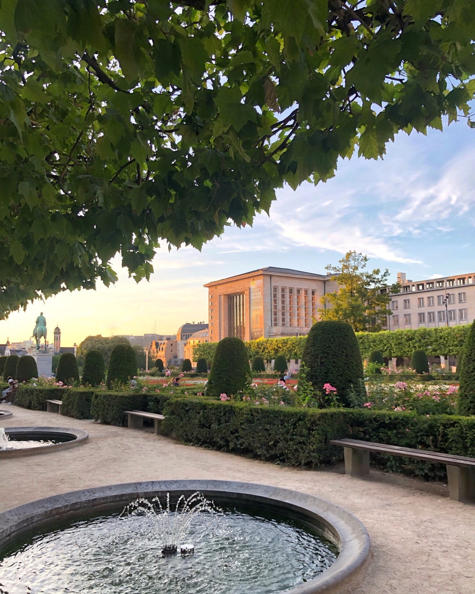 Il y a une fontaine au milieu d'un parc avec un bâtiment en arrière-plan (eau, jardin, immobilier, feuille, élément aquatique)