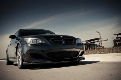 Elegante BMW M5 negro que muestra lujo y rendimiento contra un cielo dramático.