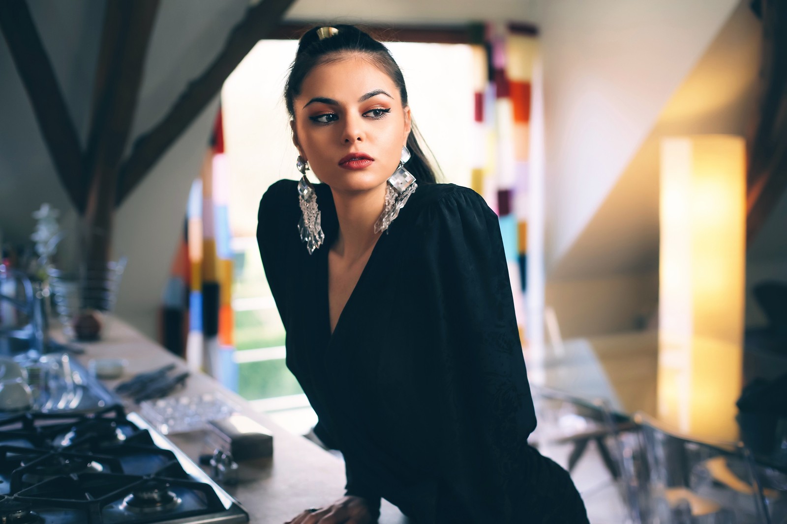 Une femme en robe noire posant dans une cuisine avec une grande fenêtre (modèle, visage, beauté, lèvre, mode)