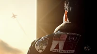 A pilot in a flight jacket gazes towards a distant aircraft under a glowing sunset, embodying the spirit of "Top Gun: Maverick.