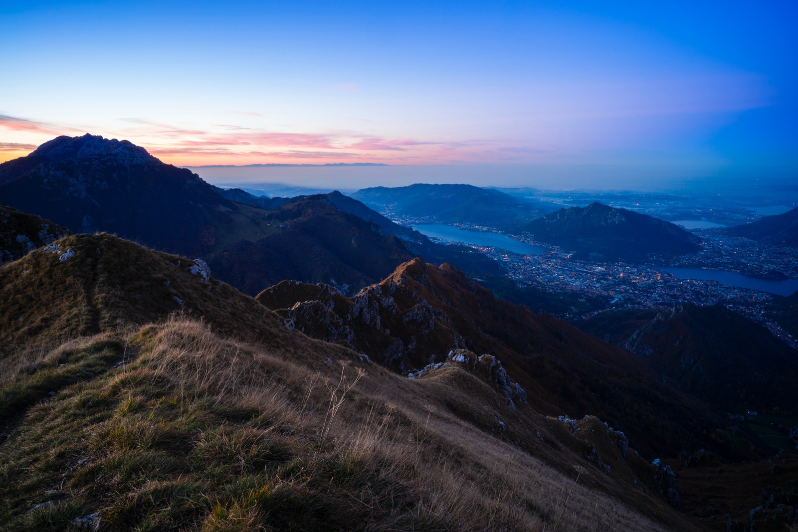 A view of a mountain with a city in the distance (cloud, atmosphere, mountain, natural landscape, terrain)