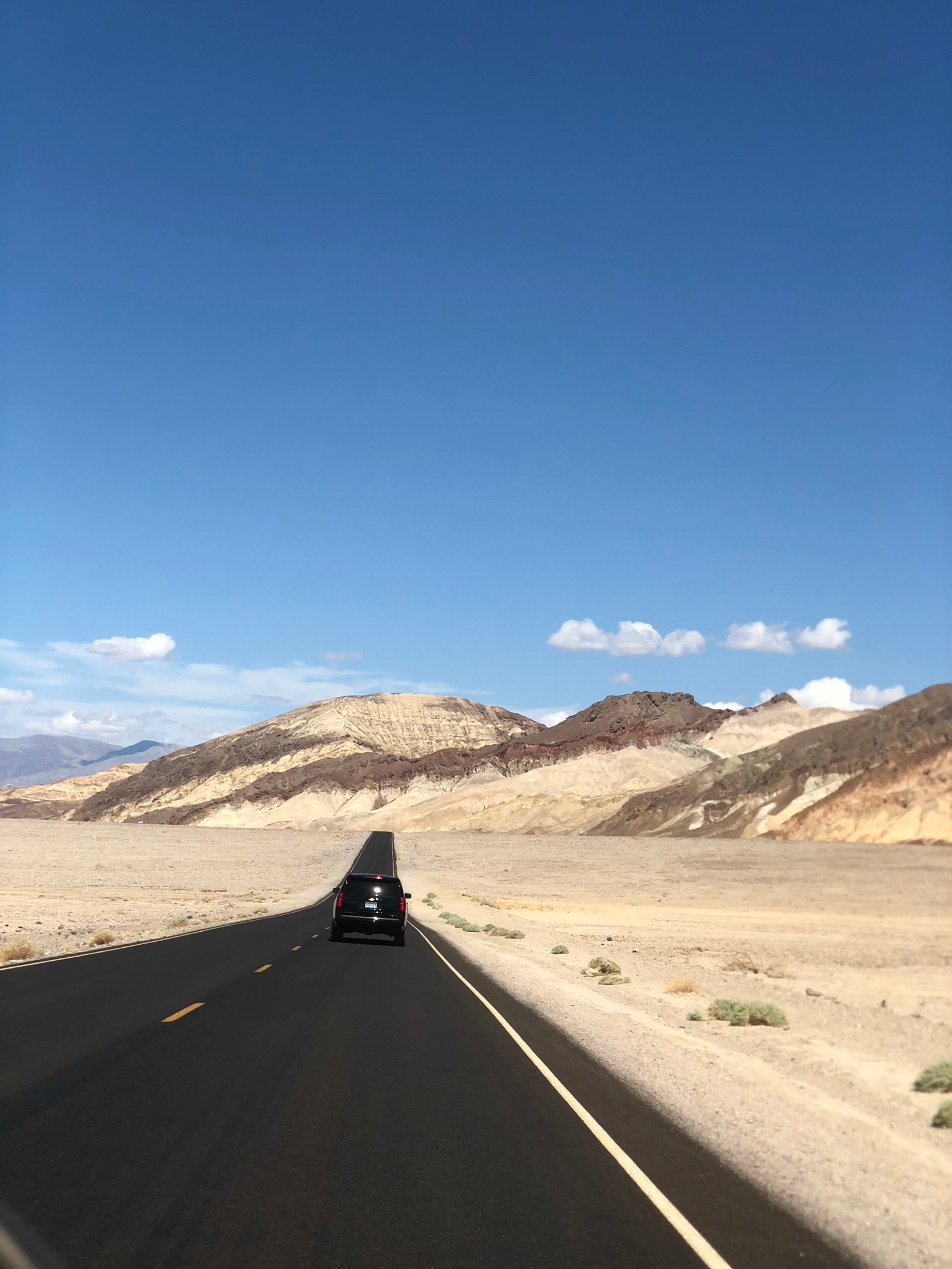 Um carro dirigindo por uma estrada desértica no meio do deserto (eua, usa, nevada, vale da morte, parque nacional do vale da morte)