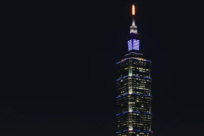 Rascacielos iluminado que se eleva sobre una metrópoli por la noche