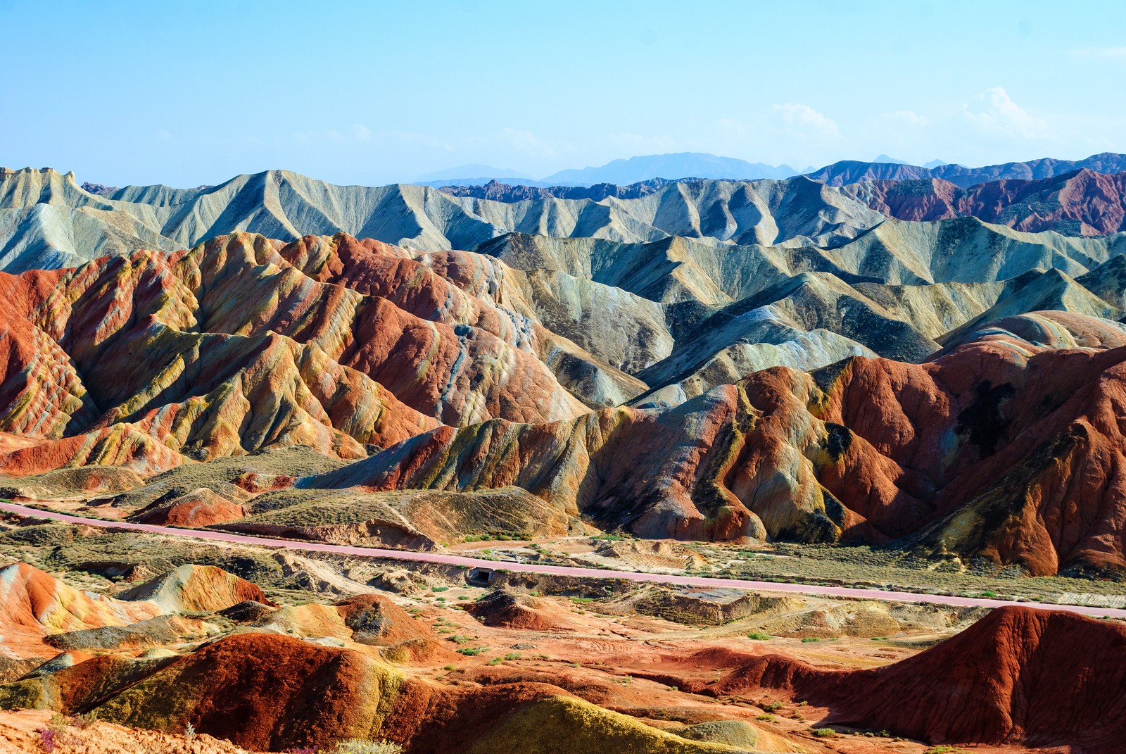 Uma vista de uma cadeia de montanhas com uma estrada sinuosa passando por ela (montanha, cadeia de montanhas, natureza, formas montanhosas, badlands)