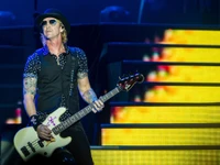 Duff McKagan actuando en el escenario con guitarra baja en un concierto de rock