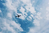 Avião deslizando por um céu azul com nuvens finas