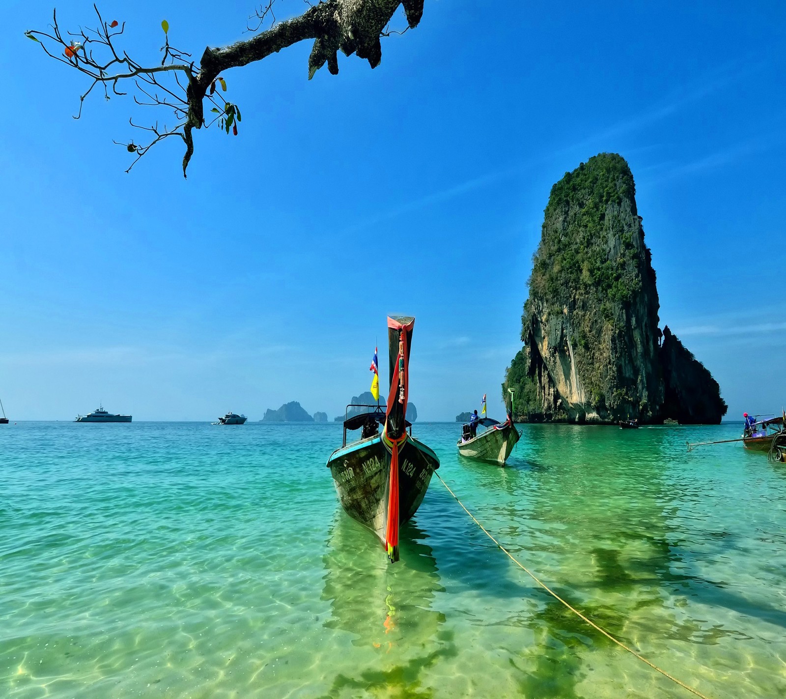 Barcos estão ancorados nas águas transparentes de uma praia tropical (bonito, paisagem)