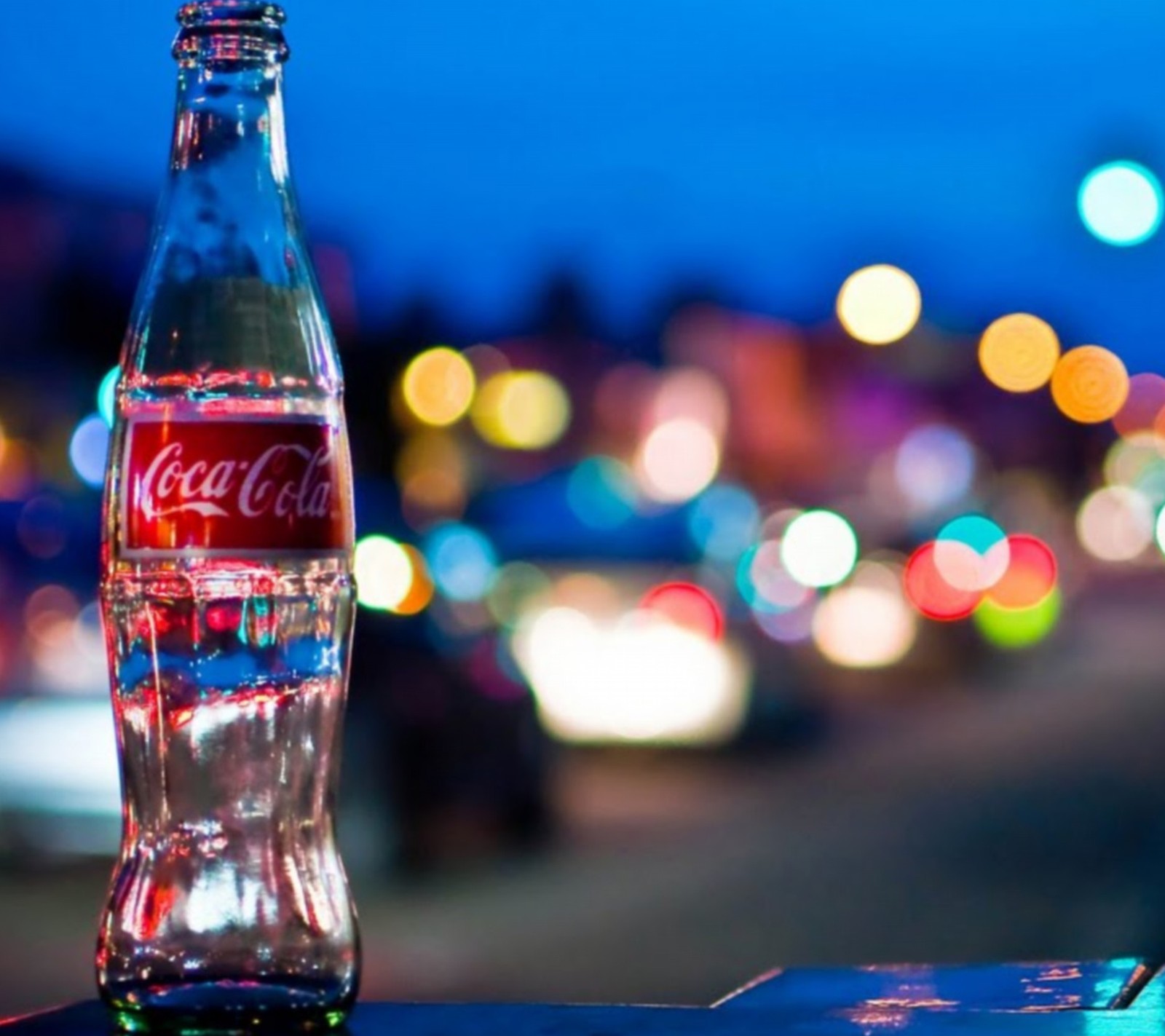 Bouteille de coca-cola floue posée sur une table devant une rue de la ville (coca, cola)