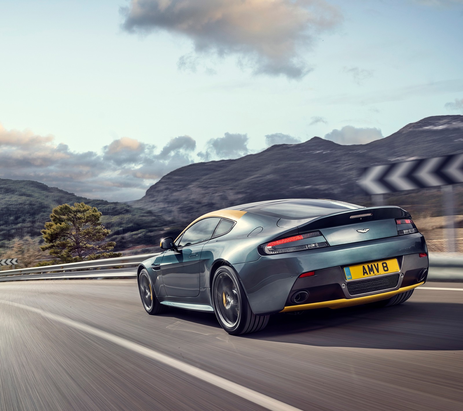 Um close de um carro dirigindo em uma estrada perto de montanhas (aston martin, estrada, velocidade, v8, vantagem)