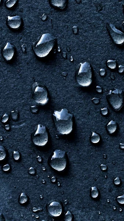 Toma macro de gotas de agua azules sobre superficie oscura