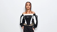 FKA twigs dans une tenue noire et blanche élégante sur fond blanc.