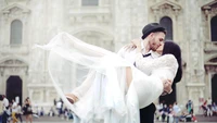 A joyful couple shares a romantic embrace during their wedding celebration, surrounded by a festive atmosphere.