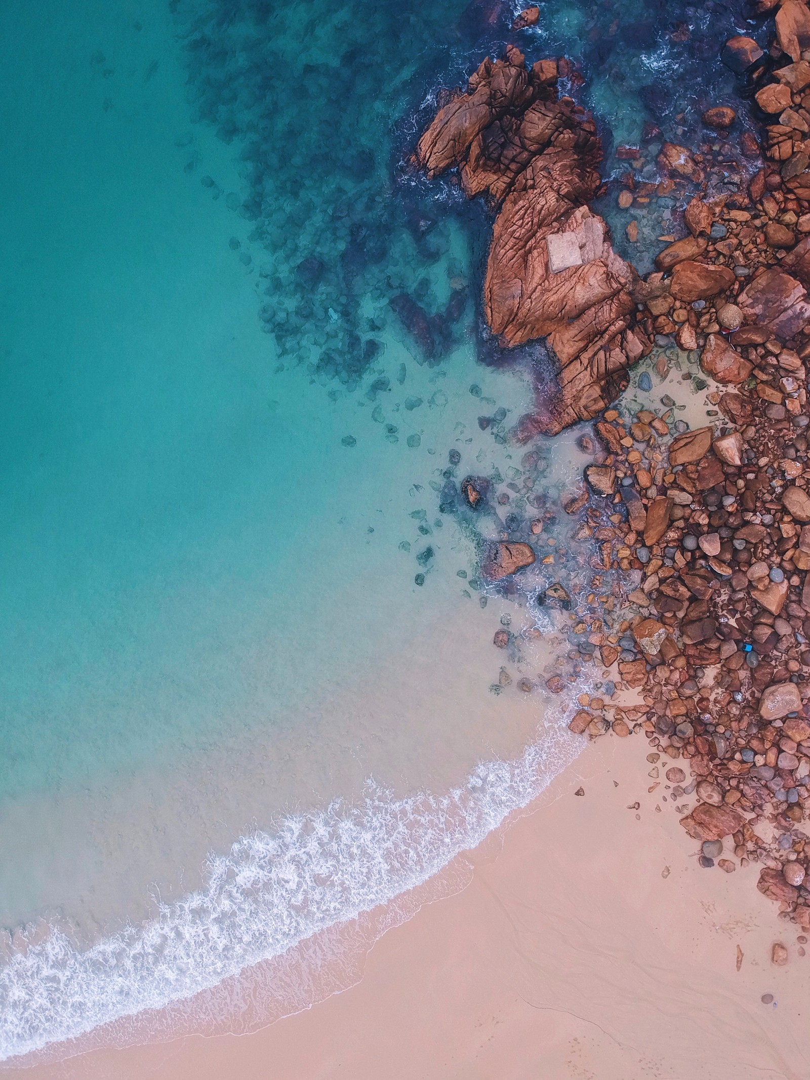 Vista aérea de una playa con un océano azul y rocas (manzana, apple wallpapers, playa, negro, ios)