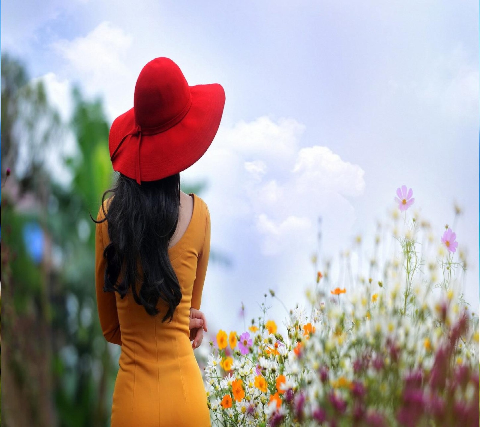 Una mujer con un sombrero rojo de pie en un campo de flores (lindo, sentimientos, niña, amor)