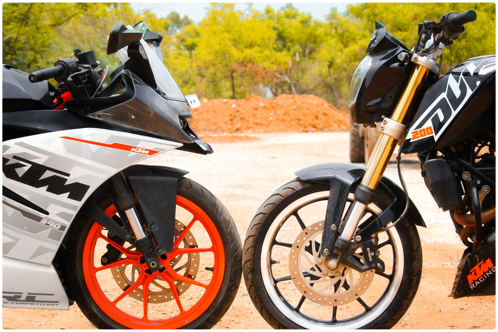 Dos motocicletas estacionadas una al lado de la otra en un camino de tierra (bicicleta, ktm rc)