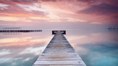 Sereno muelle de madera que se extiende hacia un océano tranquilo al atardecer